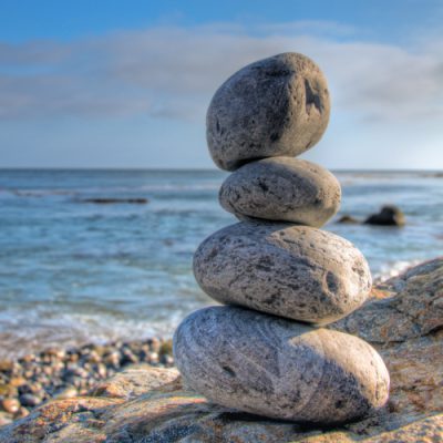 Selective focus shot of piled stones in a seashore with a blurred blue sky in the background