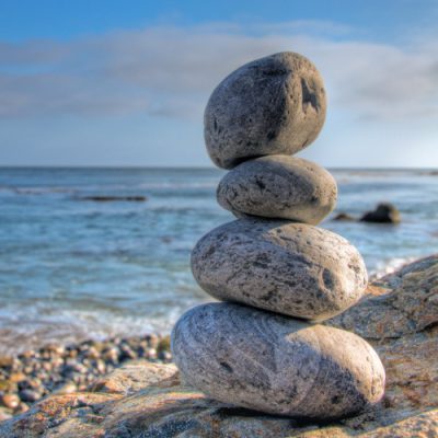 Selective focus shot of piled stones in a seashore with a blurred blue sky in the background
