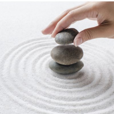 Hand stacking zen stones on the sand wellness background